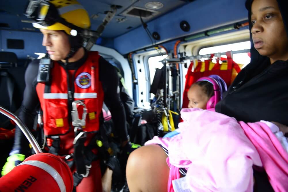U.S. Coast Guard aviation rescue swimmer and victims aboard a Coast Guard helicopter during Hurricane Harvey rescue operations in the greater Houston, Texas, metro area Aug. 28, 2017. U.S. Coast Guard photo by Petty Officer 3rd Class Johanna Strickland.